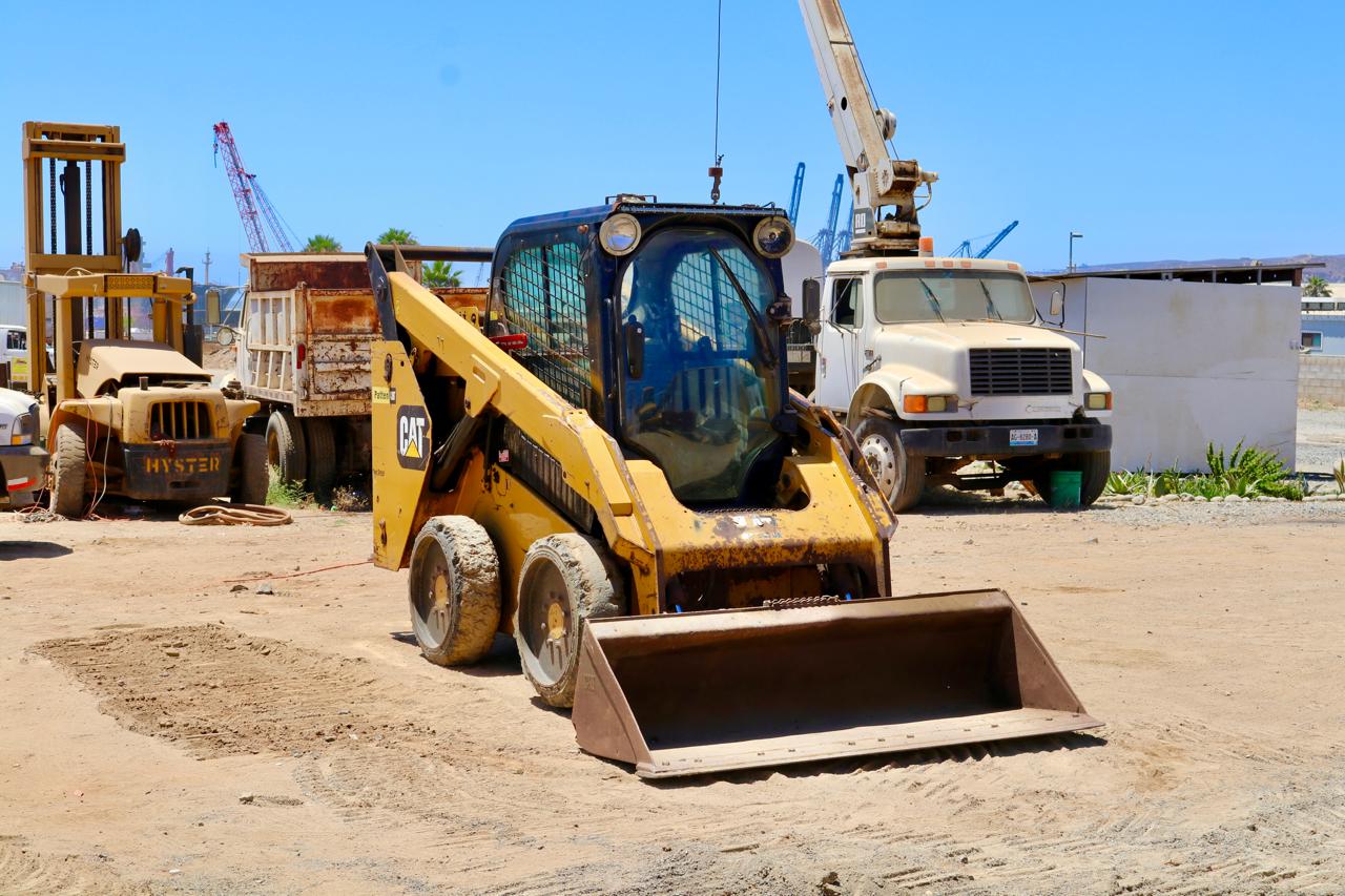 Minicargador Caterpillar y unidades de transporte.