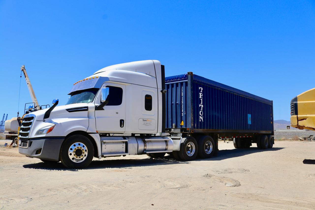 Tractocamión Freightliner con contenedor en zona portuaria.